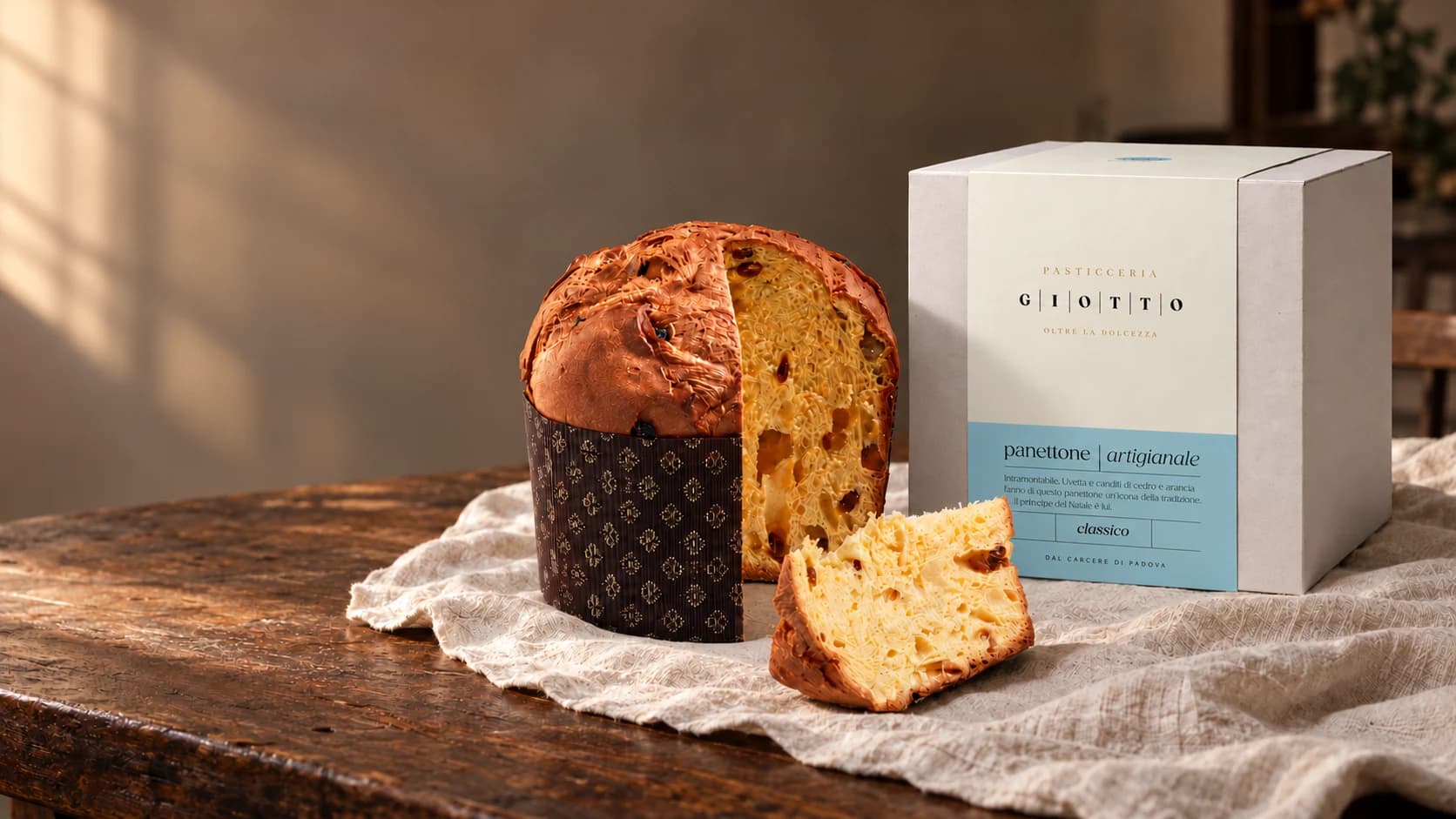 Il panettone artigianale Giotto Classico, una fetta tagliata, accanto alla sua scatola su un tavolo di legno.
